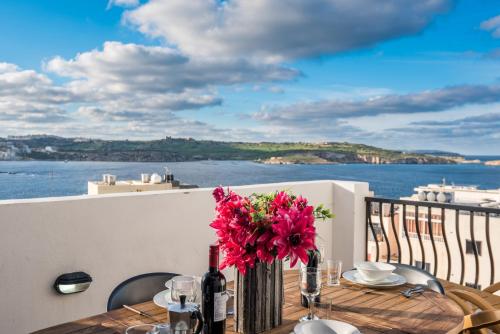 einen Tisch mit einer Blumenvase auf dem Balkon in der Unterkunft Seashells 2 bedroom Apartment with sunny terrace with stunning sea views - by Getawaysmalta in St Paul's Bay