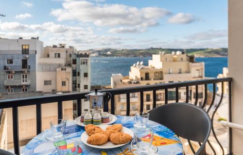 un tavolo con due piatti di cibo su un balcone di Seashells Apartments with terrace, just off the seafront in Bugibba - by Getawaysmalta a San Pawl il-Baħar