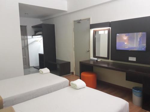 a hotel room with two beds and a television at Hotel Seri Malaysia Temerloh in Temerloh