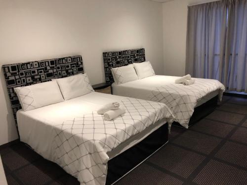 two beds in a hotel room with towels on them at Gold Reef Lodge in Johannesburg