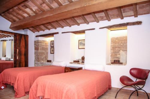 a bedroom with two beds and a chair at Casale di Nicolò in Urbino