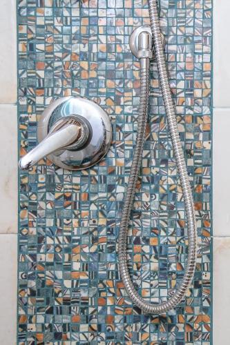 a shower with a shower head on a mosaic tile wall at Casale di Nicolò in Urbino