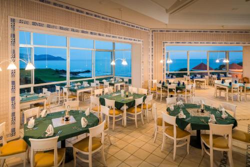 a dining room with tables and chairs and windows at Thabraca Thalasso & Diving in Tabarka