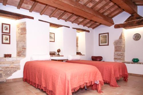 two beds in a room with white walls and wooden ceilings at Casale di Nicolò in Urbino