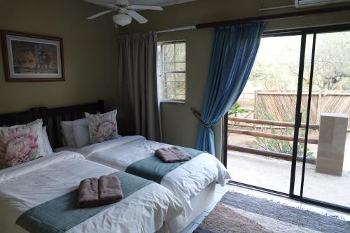 een slaapkamer met twee bedden en een groot raam bij Marloth Park Hippo House in Marloth Park