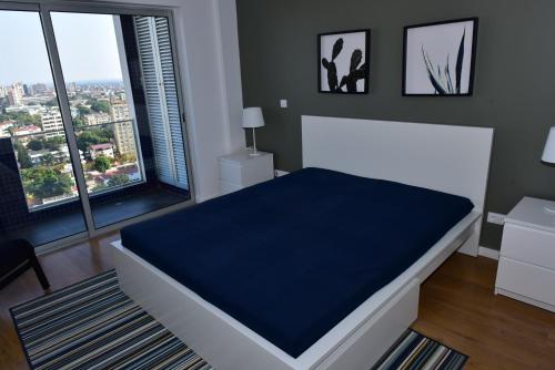 a bedroom with a large white bed with a blue blanket at Xenon Urban Apartments in Maputo