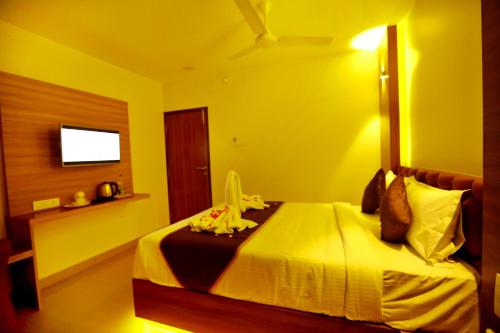a bedroom with a bed with yellow walls and a television at HOTEL KEK GRAND PARK in Chennai