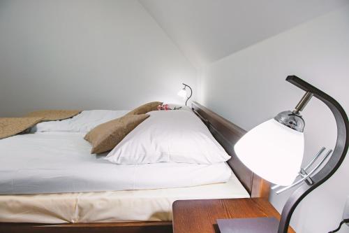 a bedroom with a bed with white pillows and a lamp at Willa 35 in Leśnica