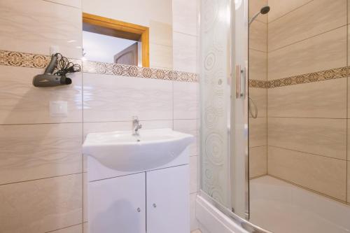 a white bathroom with a sink and a shower at Willa 35 in Leśnica