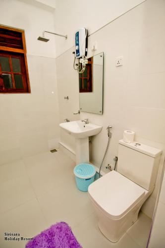 a white bathroom with a toilet and a sink at Sirisara Holiday Resort in Anuradhapura