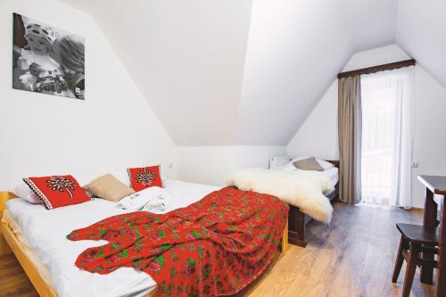 a bedroom with a bed with a red blanket on it at Willa 35 in Leśnica