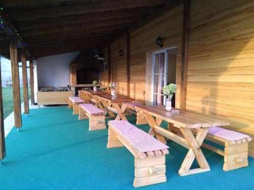 una fila de mesas y bancos de madera en un edificio en LONJSKI DVORI en Kutina