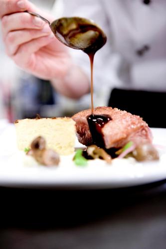 a person holding a spoon with a piece of food on a plate at Montra Odder Parkhotel in Odder