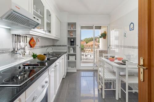 a kitchen with white cabinets and a table with chairs at Ilhéus III by An Island Apart in Funchal