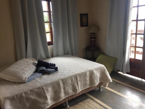 a bedroom with a bed with a blanket and two windows at Sítio e Haras Alagoense in Alagoa