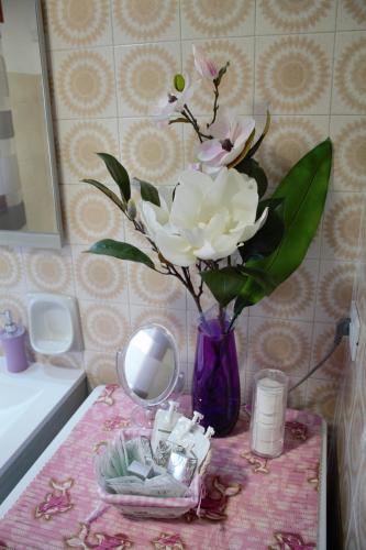 a purple vase with flowers on a table in a bathroom at Appartamento Le Magnolie in Mestre