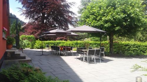 a patio with tables and chairs and umbrellas at Hotel Restaurant L Echo du Lac in Gérardmer