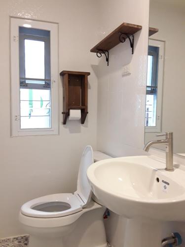 a white bathroom with a toilet and a sink at Sky cottage Bungalow in Ko Samed