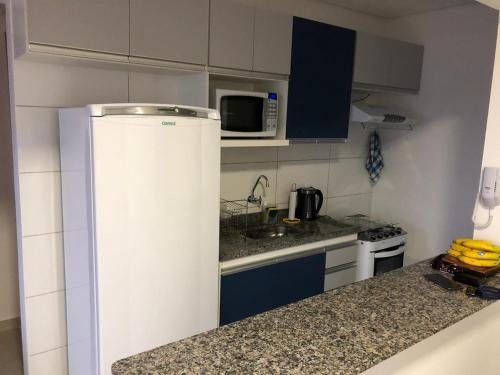 uma pequena cozinha com frigorífico e micro-ondas em Blue Ubatuba em Ubatuba