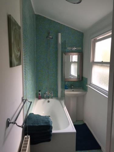 a bathroom with a white tub and green tile at Perfect 2 Bedroom Flat Shepherds Bush W12 in London