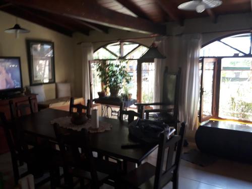 un comedor con mesa y sillas y ventanas en "Mahilo Casa" en Villa Gesell