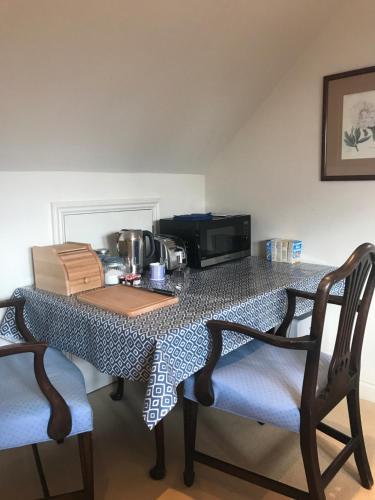 a dining room table with chairs and a microwave at The Countryside Annexe in Pulborough