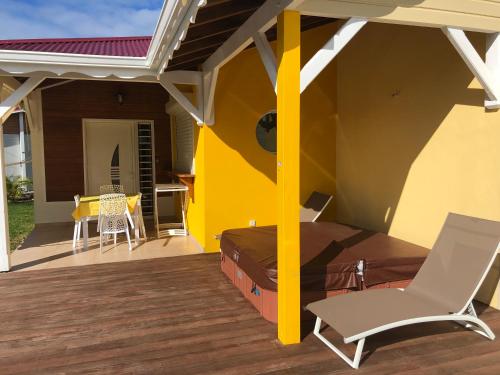 a patio with a bed and chairs on a deck at Gîte étoile du matin Grand-bourg de Marie-galante in Grand-Bourg