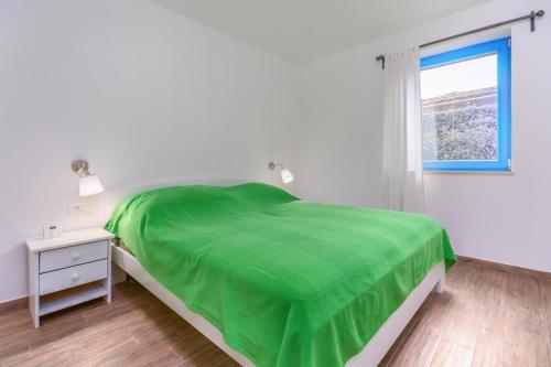 a white bedroom with a green bed and a window at Dajla 66 in Dajla