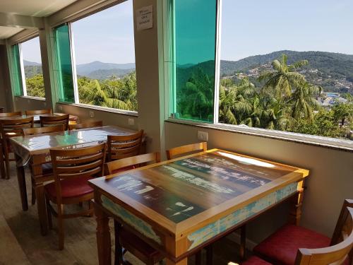 un restaurante con mesas, sillas y ventanas grandes en Pousada Do Galdino, en Blumenau