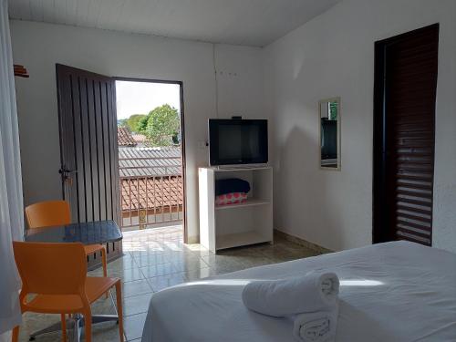 a bedroom with a bed and a tv and a table at Pouso do Rio in Pirenópolis