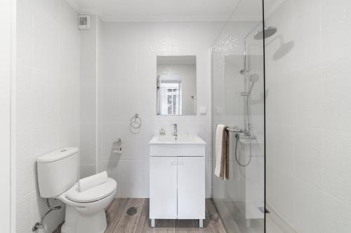 a white bathroom with a toilet and a sink at Funchal City Apartments in Funchal