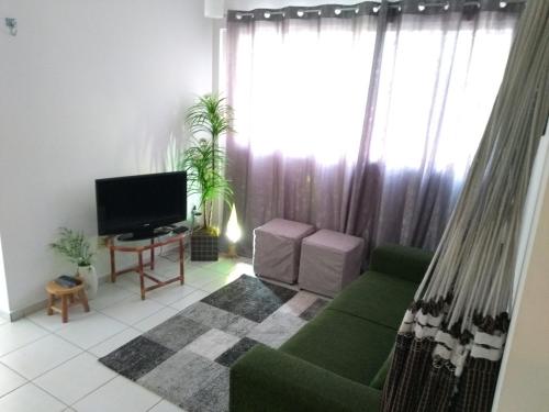 a living room with a green couch and a television at Natal RN Apartamento in Parnamirim