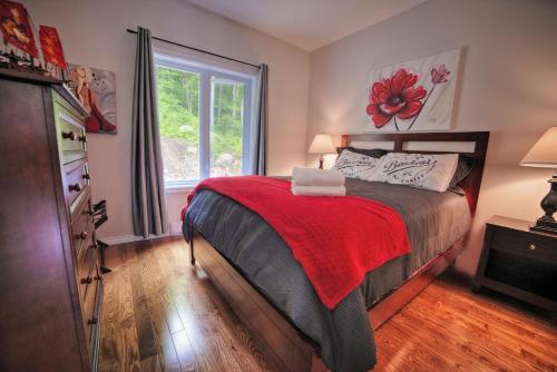 ein Schlafzimmer mit einem Bett mit einer roten Decke und einem Fenster in der Unterkunft Chalet Potvin Bouchard in LʼAnse-Saint-Jean