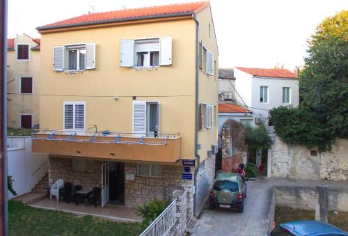 a house with a car parked in front of it at Apartments & Rooms Andrea 2 in Zadar