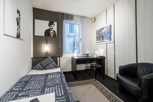 マールブルク・アン・デア・ラーンにあるホテル タスカルムのベッドとデスクが備わるホテルルームです。