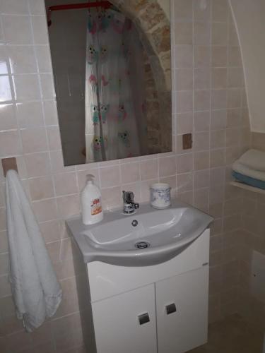 a bathroom with a white sink and a mirror at Trulletto dei sogni in Alberobello