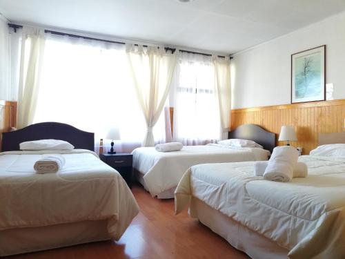 a hotel room with two beds and two windows at Agostini Hotel in Puerto Natales