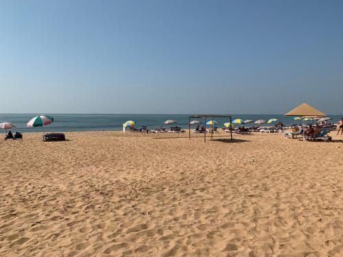a beach with umbrellas and people sitting on the sand at Casa Da Praia in Candolim