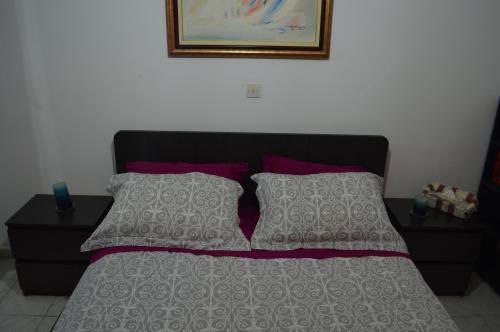 uma cama com uma cabeceira preta e almofadas roxas em Apartment in the Center of Aigio Dimitropoulos em Aigio