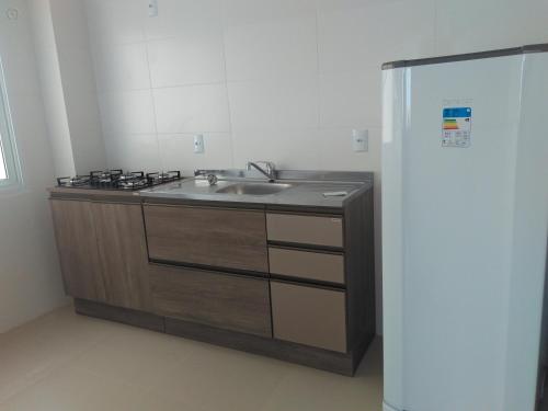 a kitchen with a sink and a refrigerator at Residencial Beira Mar in Cassino