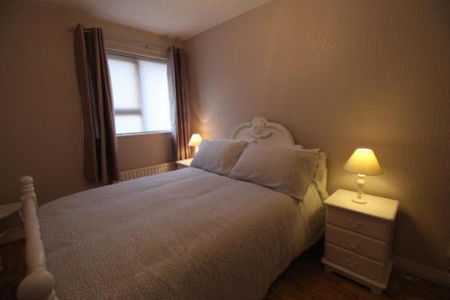 a bedroom with a bed and a window and two lamps at Wayside in Tandragee