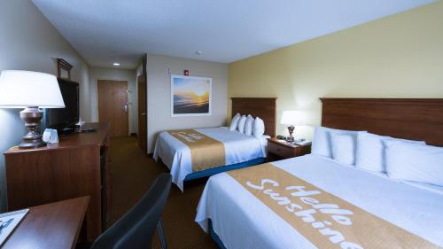 a hotel room with two beds and a desk at Days Inn by Wyndham Greensboro NC in Greensboro