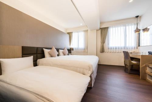 a hotel room with two beds and a desk at Shin Yuan Park Hotel in Hsinchu City