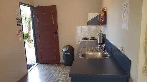 a small kitchen with a sink and a stove at Palm Court Motel in Otorohanga