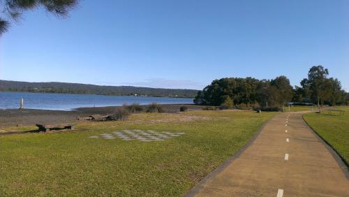 a path in a park next to a body of water at Kincumber House in Kincumber