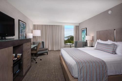 a hotel room with a large bed and a television at Best Western Plus Agate Beach Inn in Newport