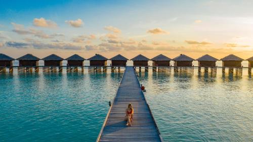 uma mulher parada numa doca no meio da água em Filitheyo Island Resort em Filitheyo