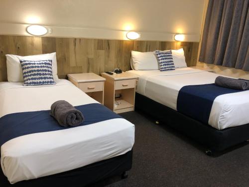 a hotel room with two beds and two tables at Wattle Tree Motel in Cootamundra