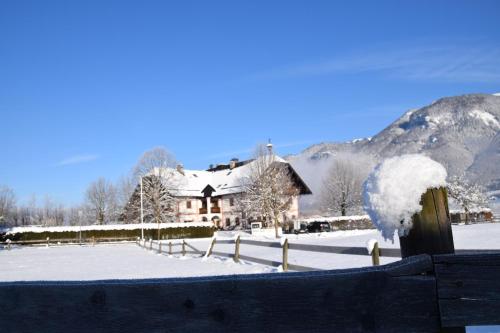 a house in the snow with a fence at Seehotel Huber in Sankt Gilgen