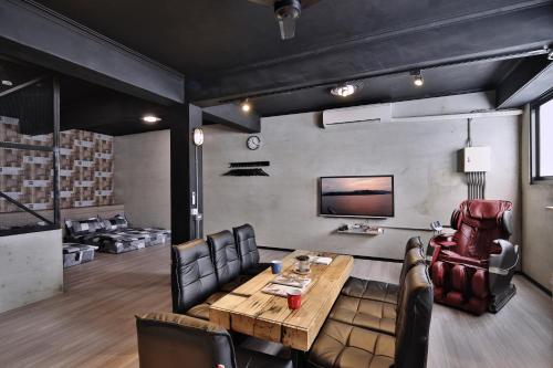 a living room with a wooden table and leather chairs at 幸福滿屋 台南6人至40人包棟包層民宿 中西區花園 夜市附近住宿3分鐘 in Tainan
